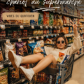 Femme poussant un caddie plein de courses au supermarché, souriante.